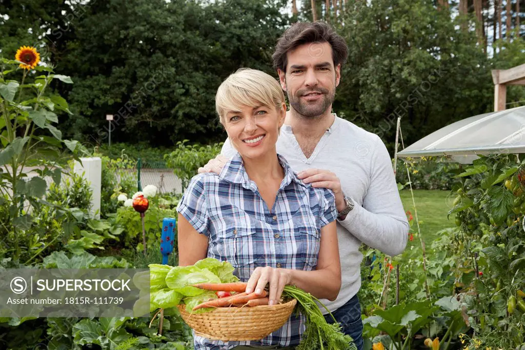 Germany, Bavaria, Nuremberg, Mature couple with vegetables in garden