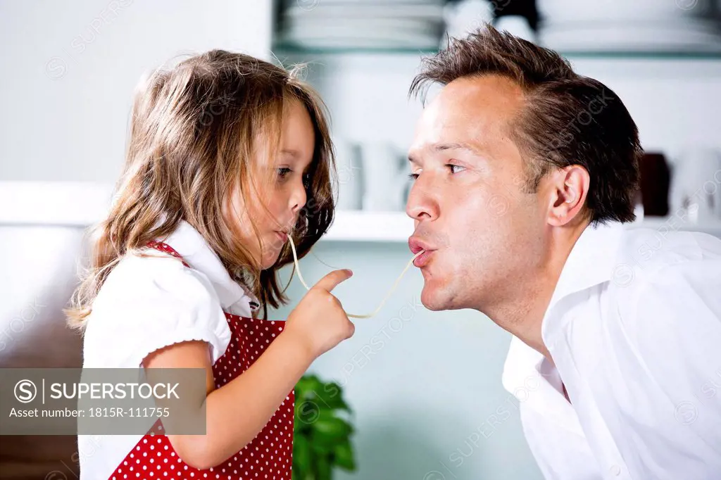 Germany, Daughter eating noodles with father in kitchen
