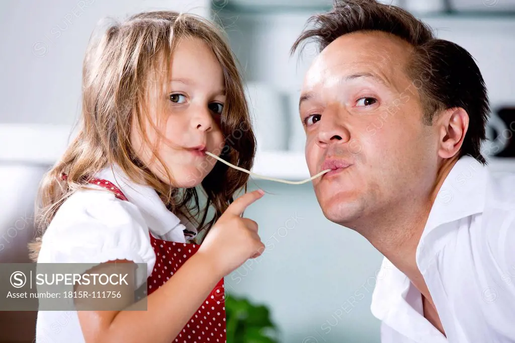 Germany, Daughter eating noodles with father in kitchen