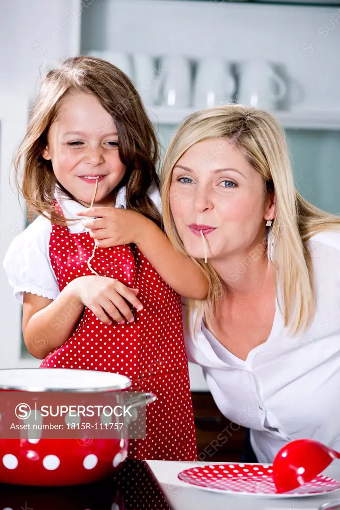 Germany, Mother and daughter eating noodles in kitchen
