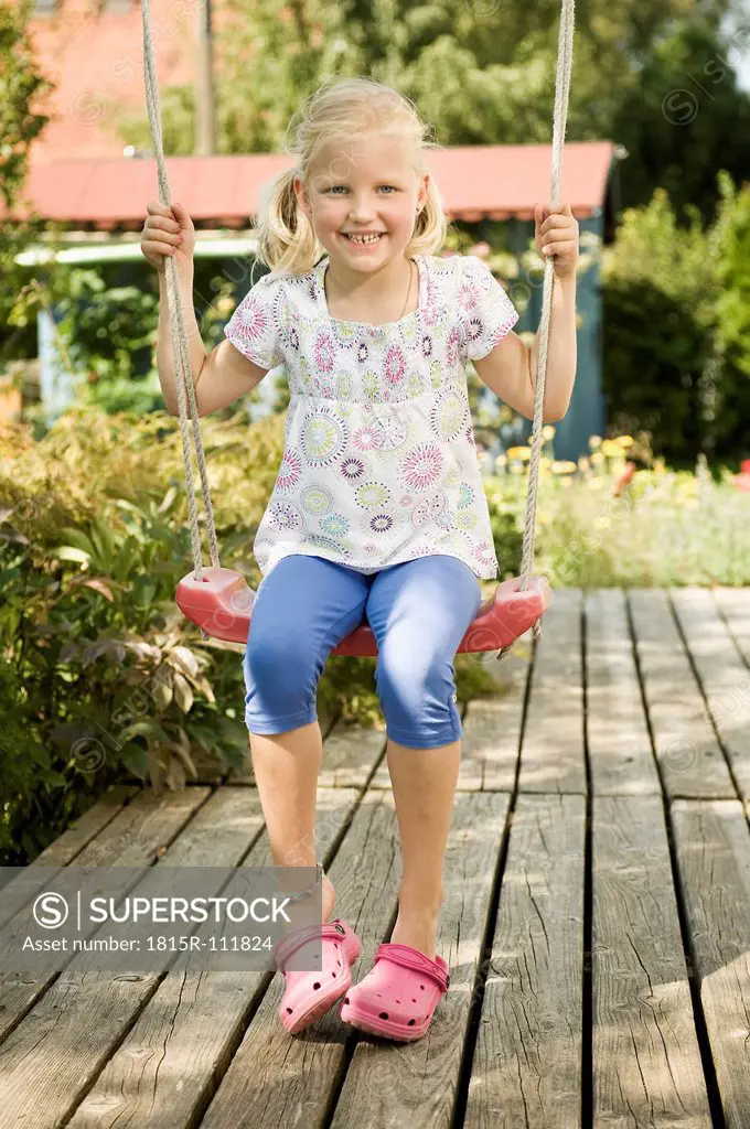 Germany, Bavaria, Girl swinging on swing, smiling, portrait