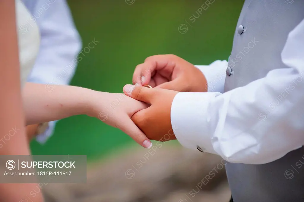 USA, Texas, Groom instering ring to bride, close up