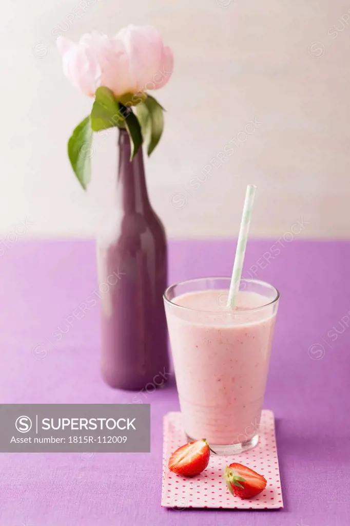 Glass of strawberry smoothie with peonie, close up