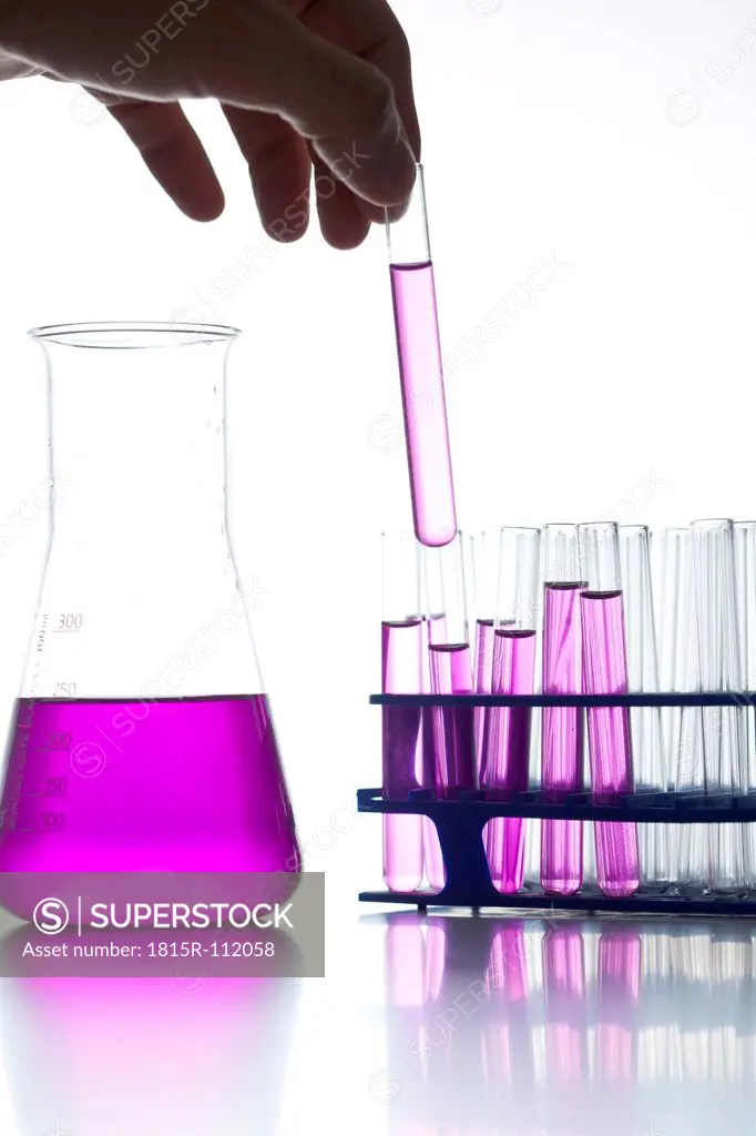 Chemist holding test tube against white background, close up
