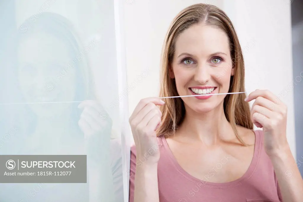 Germany, Close up of young woman holding dental floss