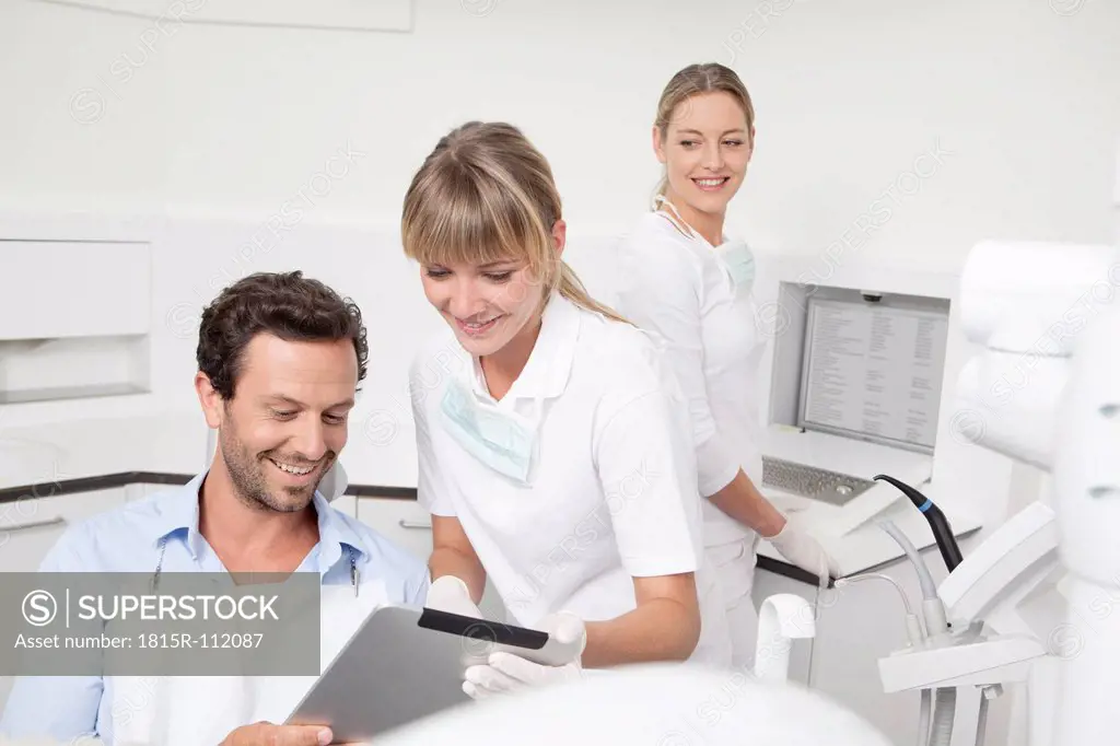 Germany, Dentist showing clipboard to patient