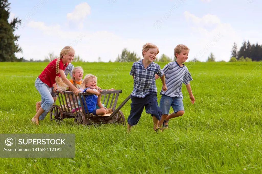 Germany, Bavaria, Group of children playing with hand cart