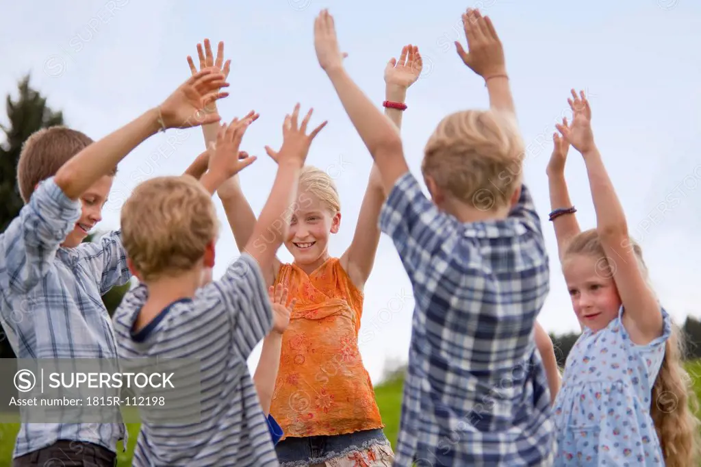 Germany, Bavaria, Group of children raising hands in air