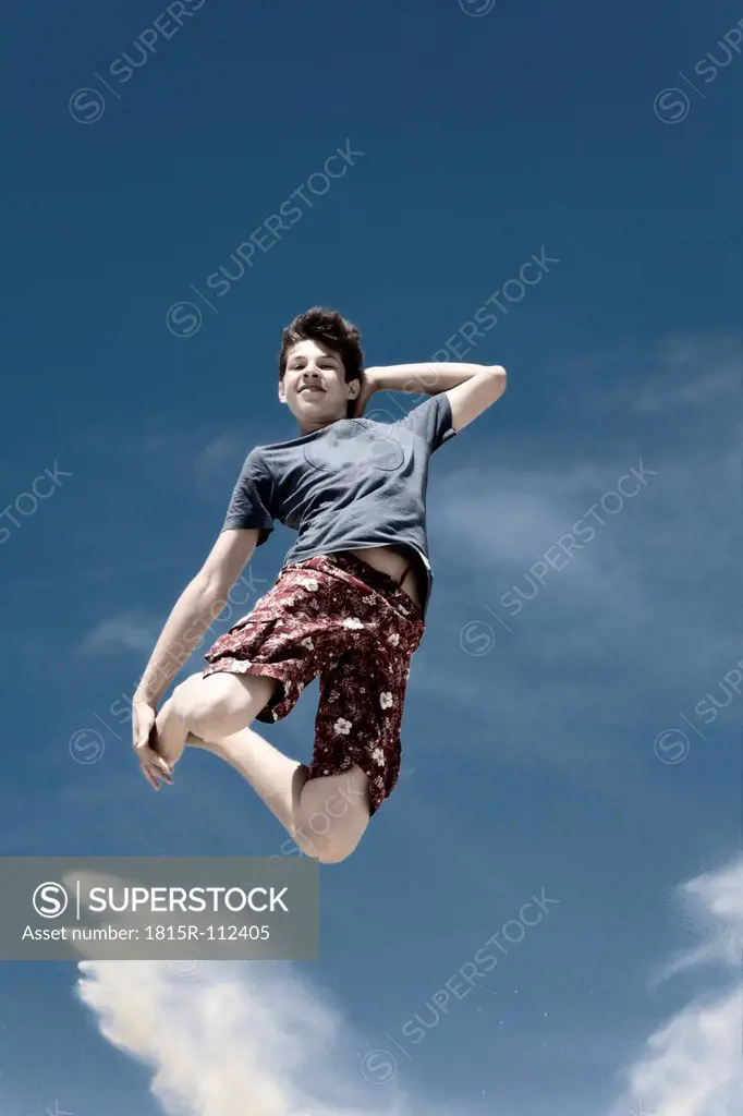 France, Teenage boy jumping on sand dune