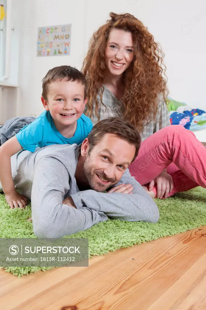 Germany, Berlin, Family lying on floor, smiling, portrait