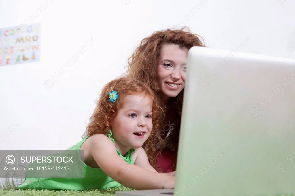 Germany, Berlin, Mother and daughter using laptop on floor