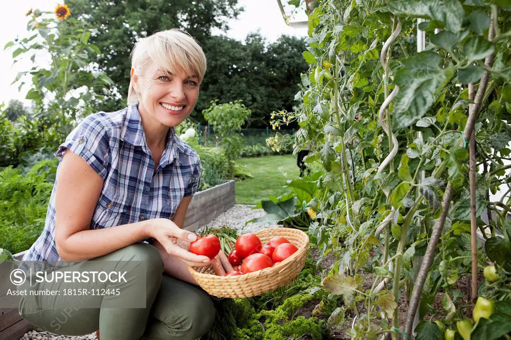 Germany, Bavaria, Nuremberg, Mature woman with vegetables in garden