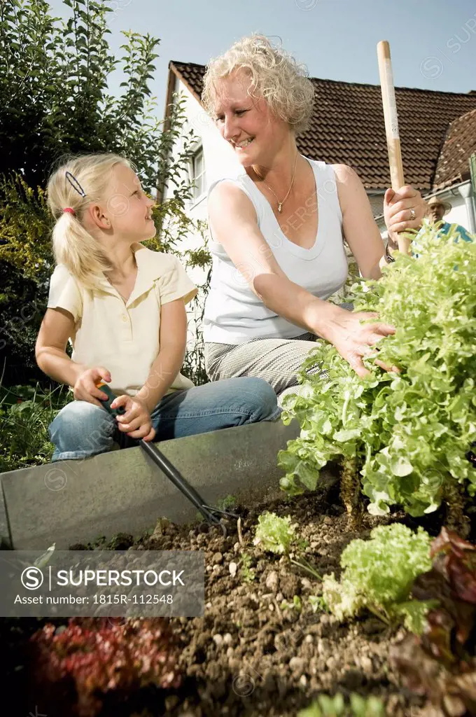 Germany, Bavaria, Grandmother with children working in vegetable garden