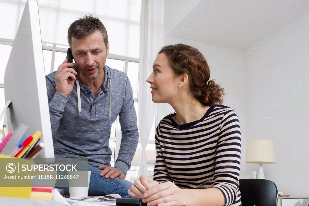 Man and woman at at desk with computer and telephone