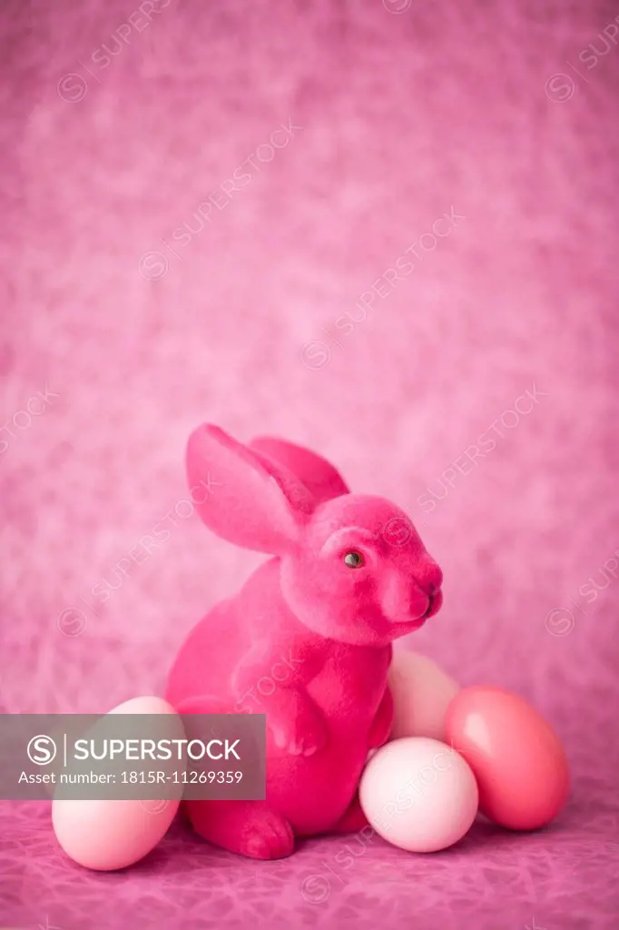 Pink Easter bunny with Easter eggs in front of pink background