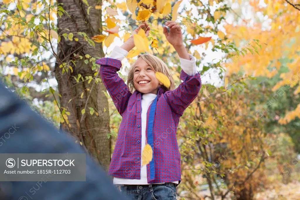 Germany, Leipzig, Father and son playing with leaves, smiling