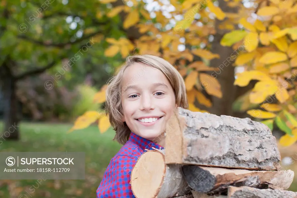 Germany, Leipzig, Boy holding firewood, smiling