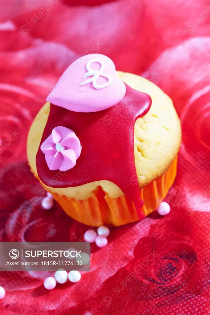 Decorated muffin in muffin paper on red floral design