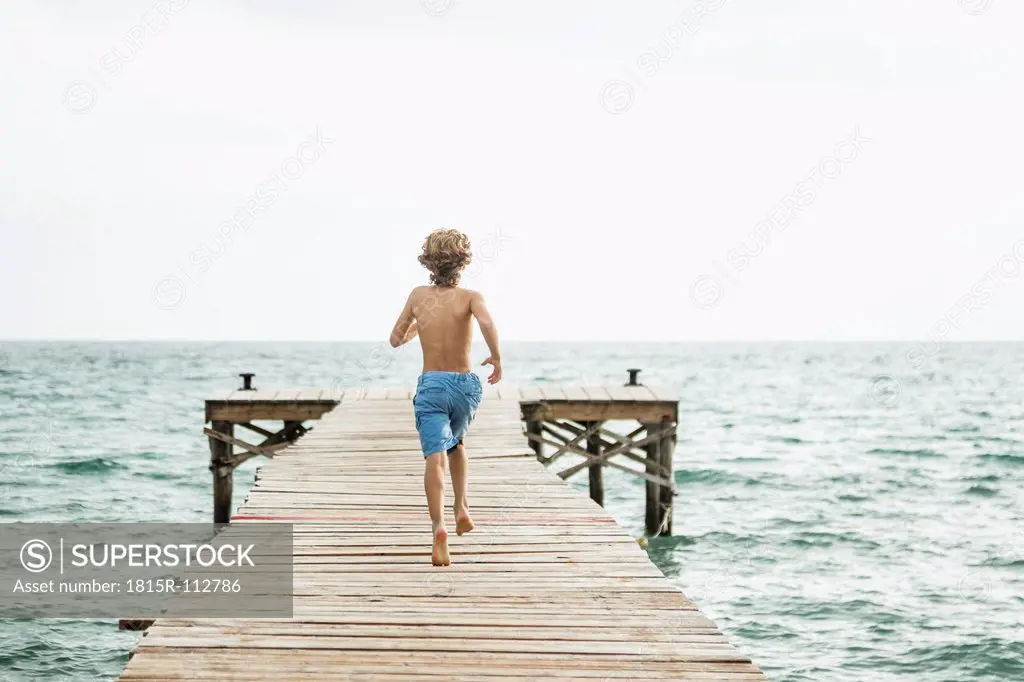 Spain, Boy running on jetty at the sea