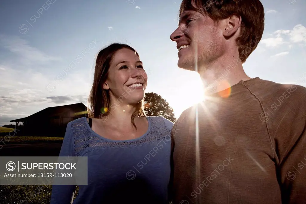 Germany, Bavaria, Couple standing in field, smiling