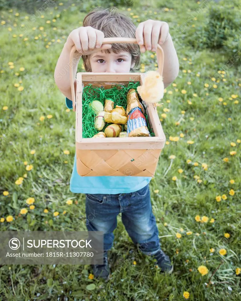 Little boy showing his basket with chocolate Easter bunnies