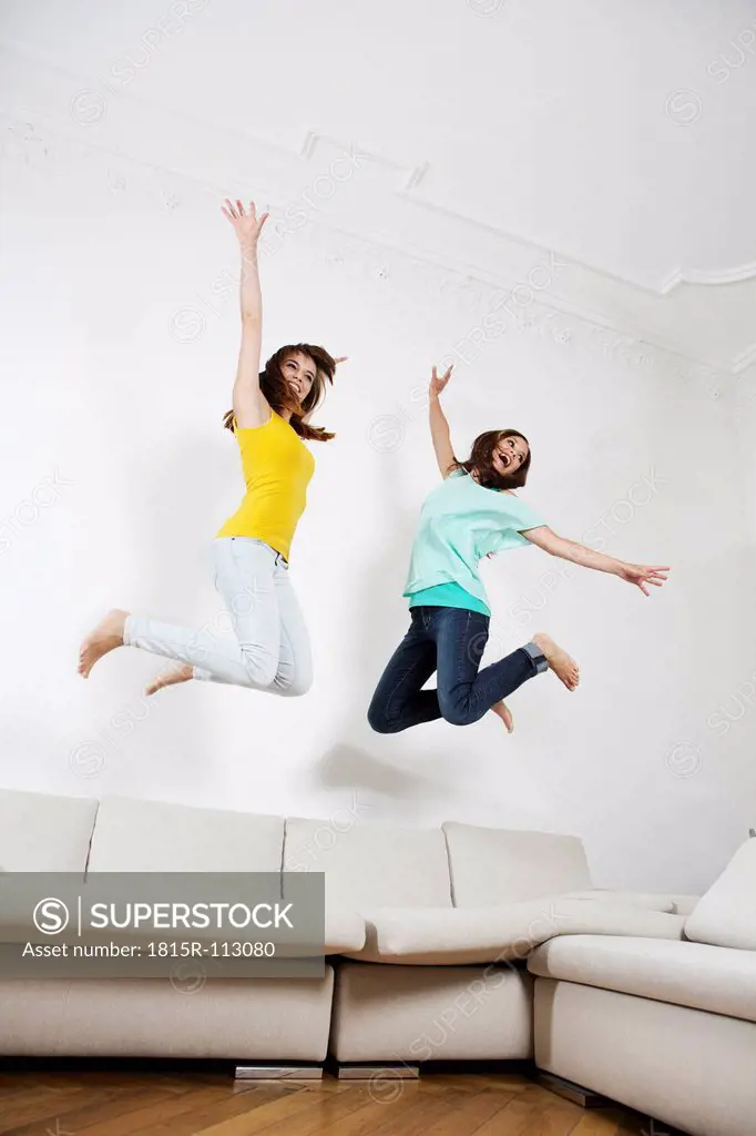 Germany, Berlin, Young women having fun and jumping on couch