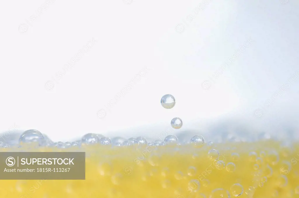 Bubbles in glass of water with lemon slice, close up