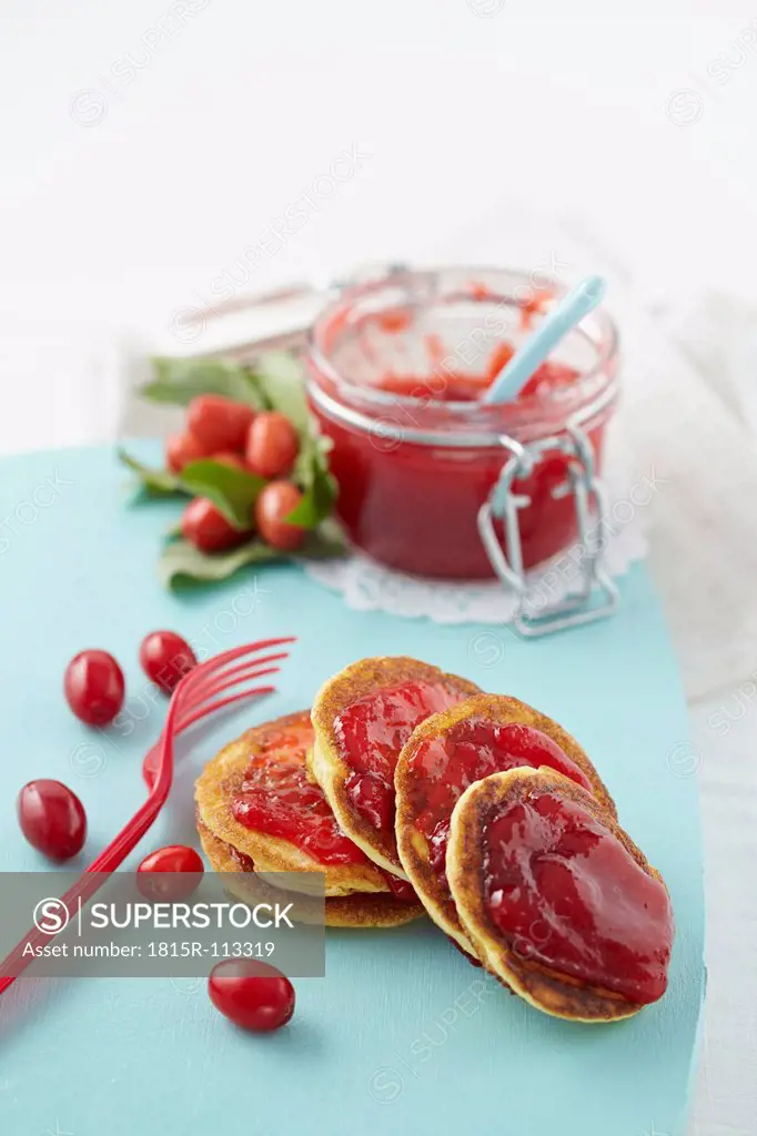 Cornel cherry jam with pancakes on chopping board