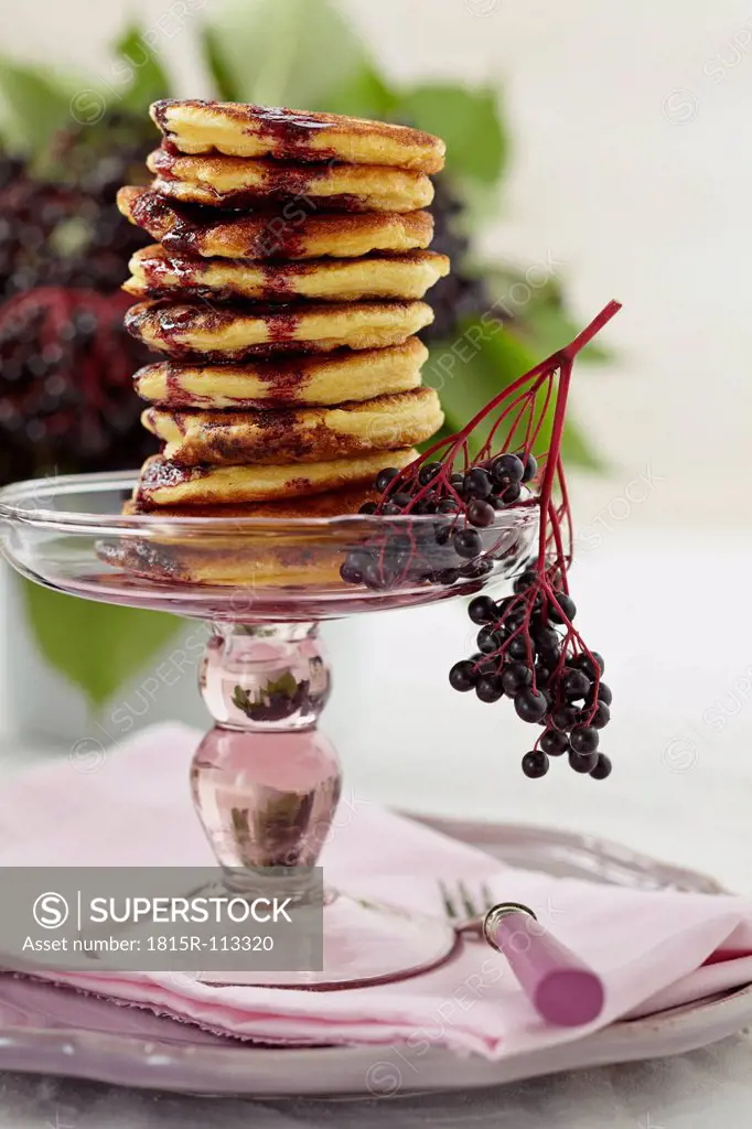 Stacked pancakes on cakestand with elderberry on plate