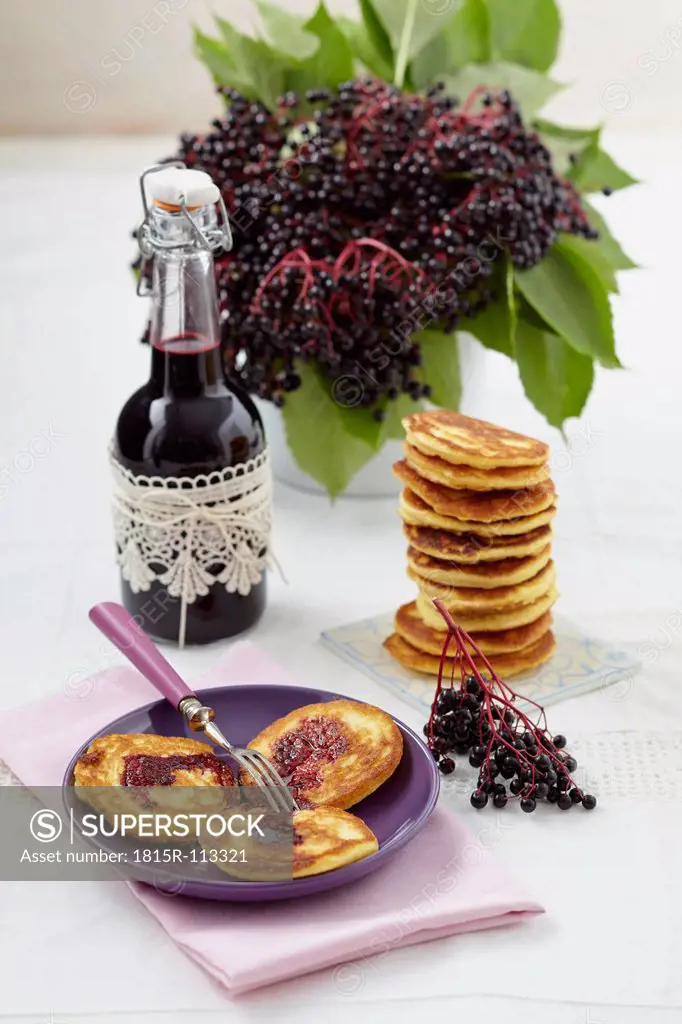 Pancakes with elderberry syrup on table