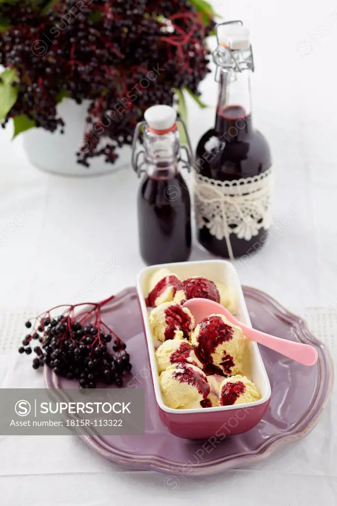 Ice cream in tray with elderberry syrup in bottles