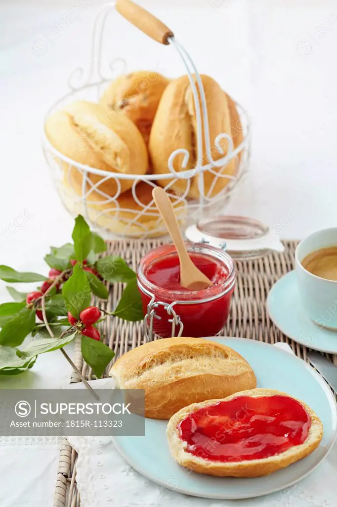Cornel cherry jam with bread rolls and coffee on table