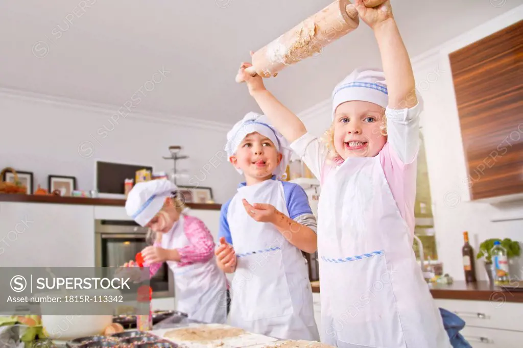 Germany, Girls and boy baking cup cakes in kitchen