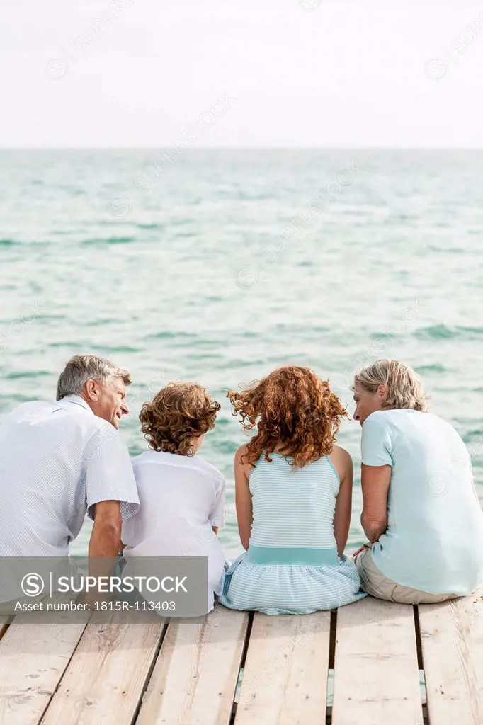 Spain, Grandparents with grandchildren sitting on jetty