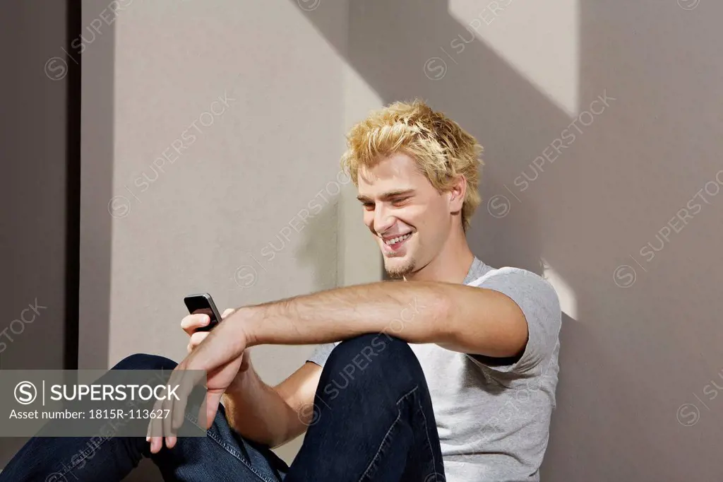 Germany, Berlin, Young man using smart phone, smiling