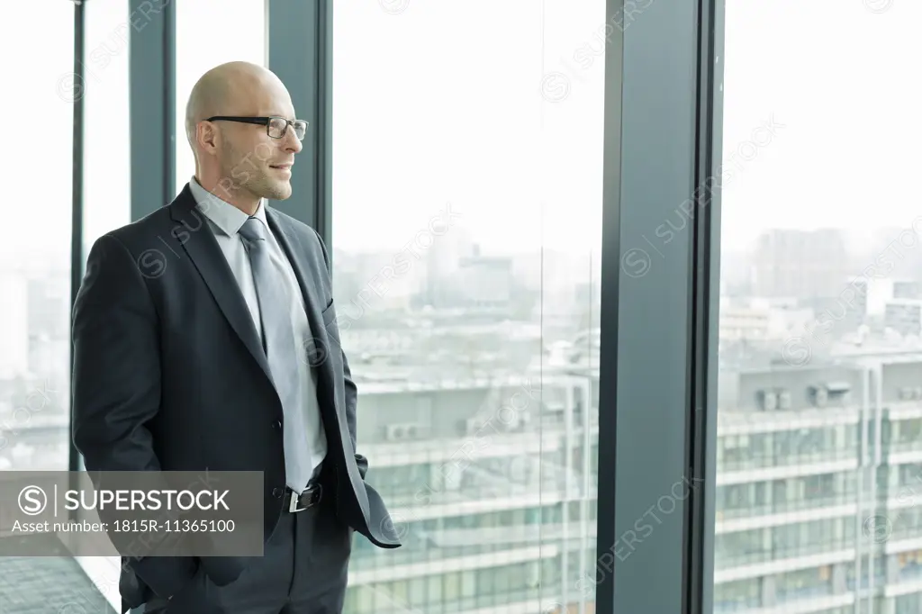 Confident businessman on office floor looking out of window