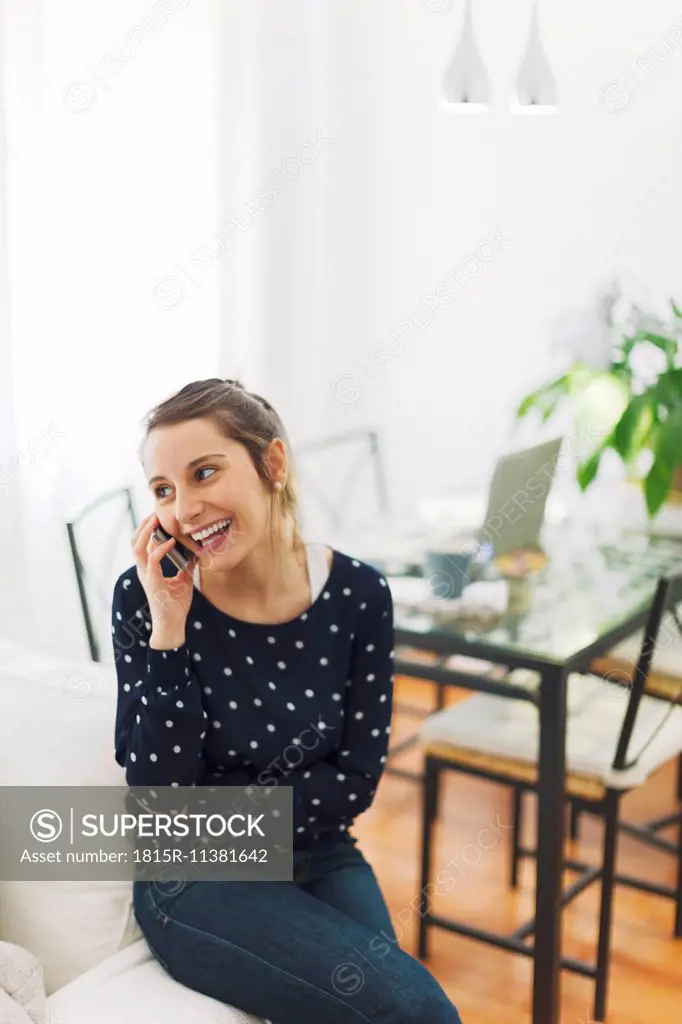 Young woman telephoning with smartphone at home