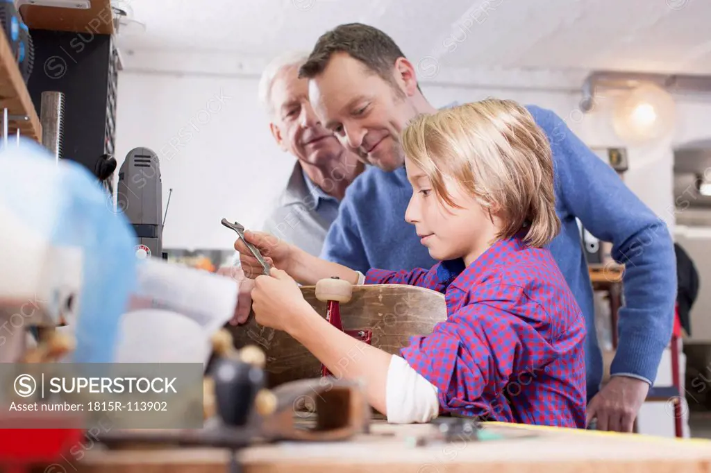 Germany, Leipzig, Grandfather, father and son repairing skateboard