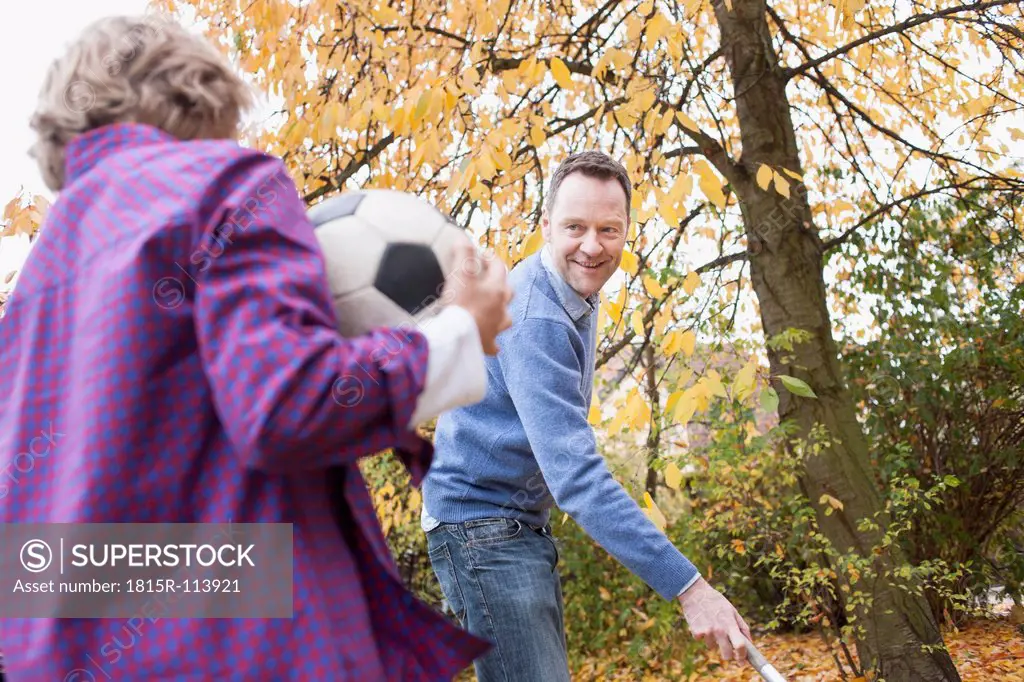 Germany, Leipzig, Boy holding football, father collecting leaves