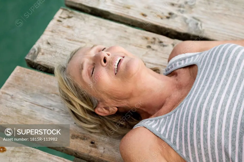 Spain, Senior woman relaxing on jetty at the sea