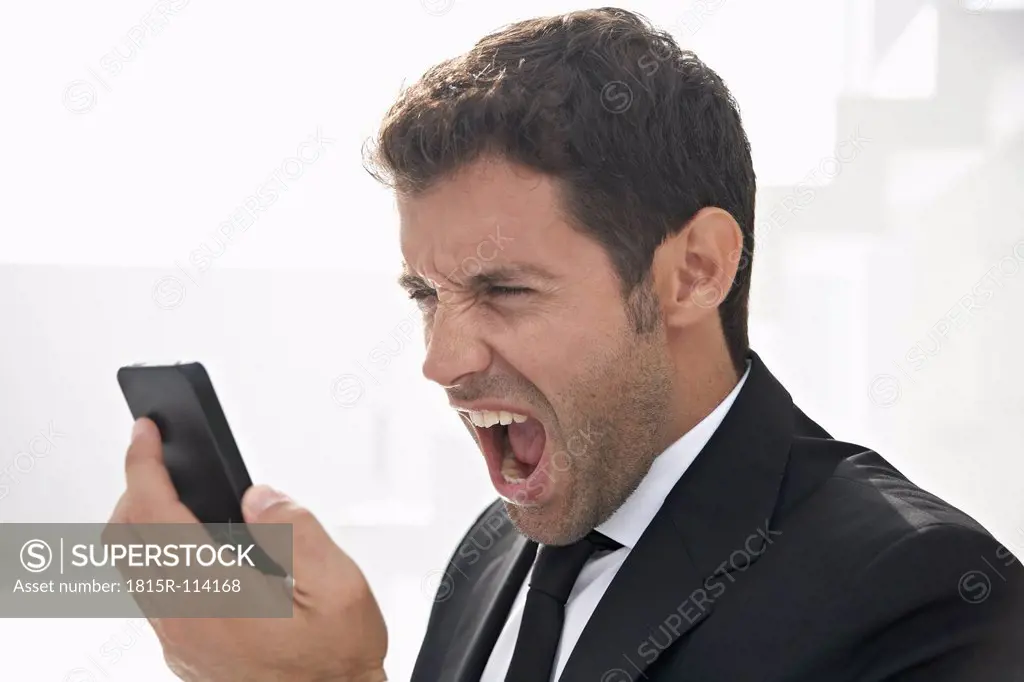Spain, Businessman shouting on mobile phone