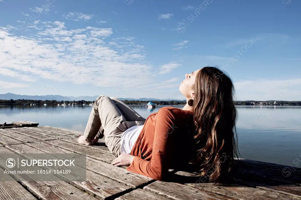 Germany, Bavaria, Young woman sitting on jetty