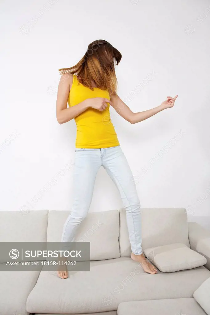 Germany, Berlin, Young woman playing air guitar