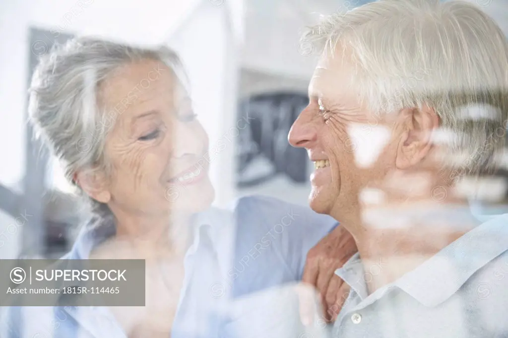 Spain, Senior couple behind window, smiling