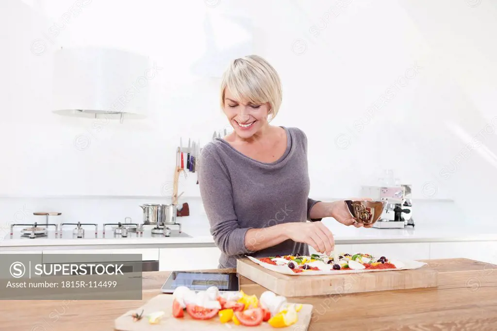 Germany, Bavaria, Munich, Woman preparing pizza in kitchen