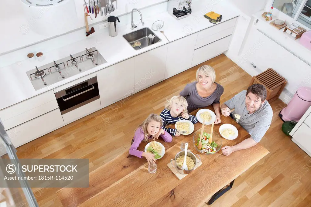 Germany, Bavaria, Munich, Family eating spaghetti in kitchen