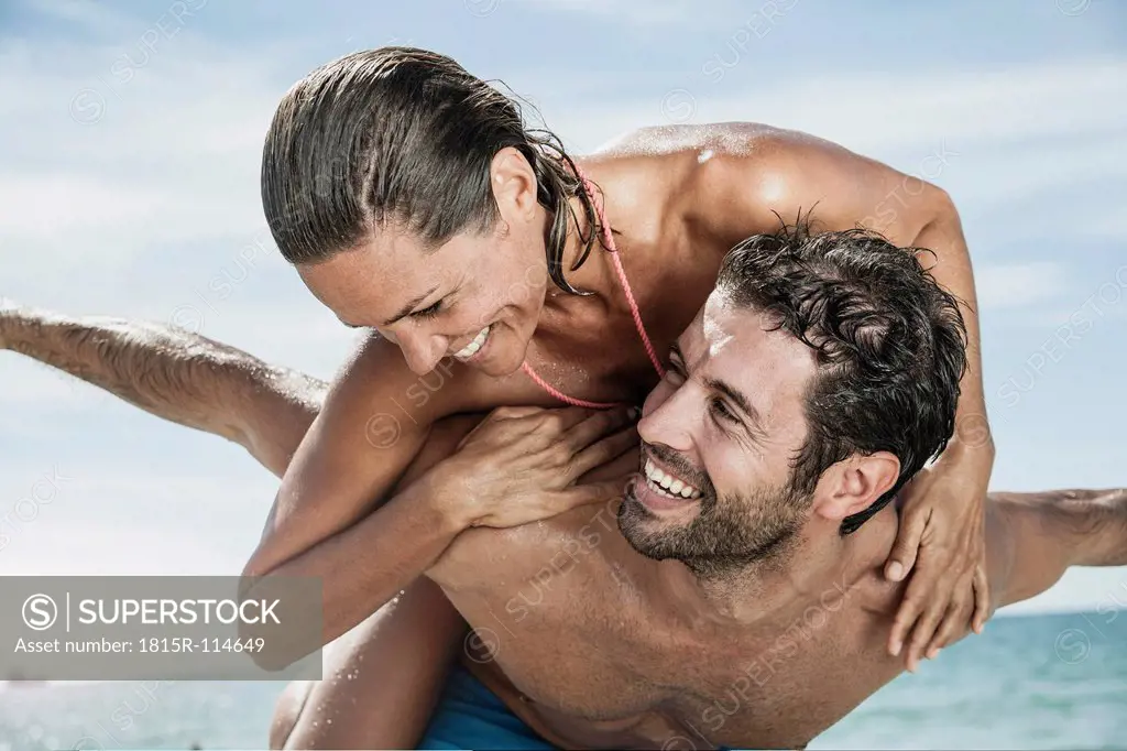 Spain, Mid adult man giving piggy back ride to woman