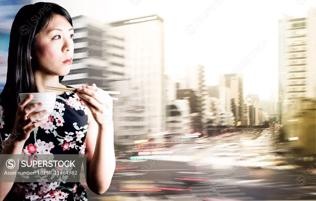Asian woman with chopsticks and blurry Tokyo in the background