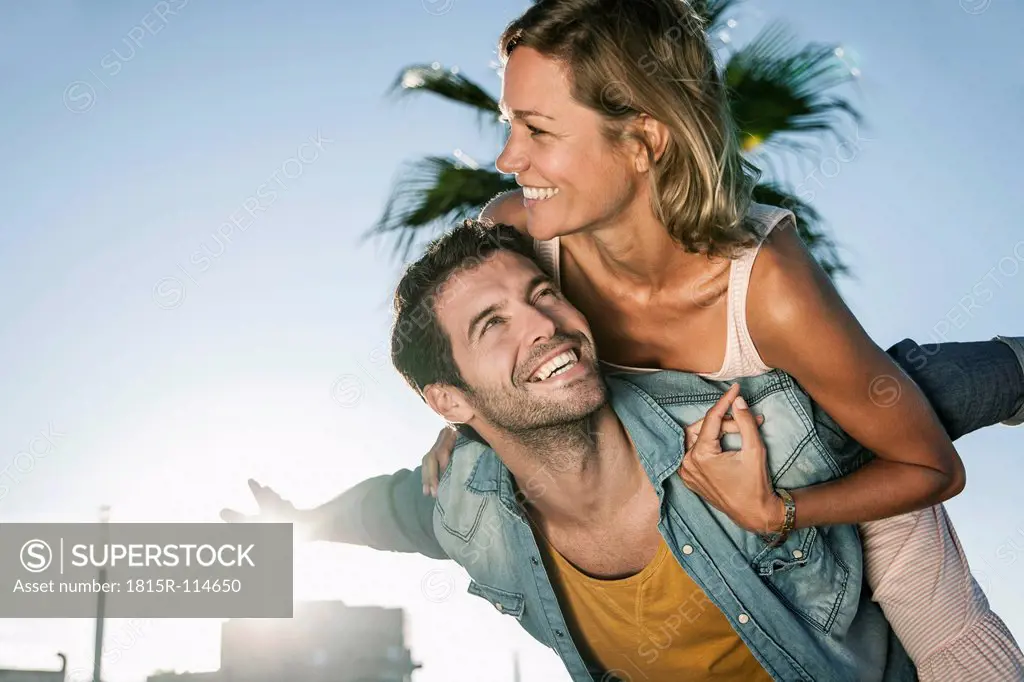 Spain, Mid adult man giving piggy back ride to woman