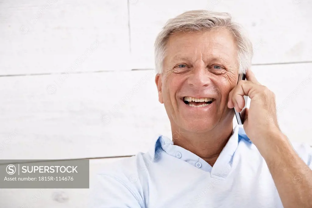 Spain, Senior man talking on mobile, smiling, portrait